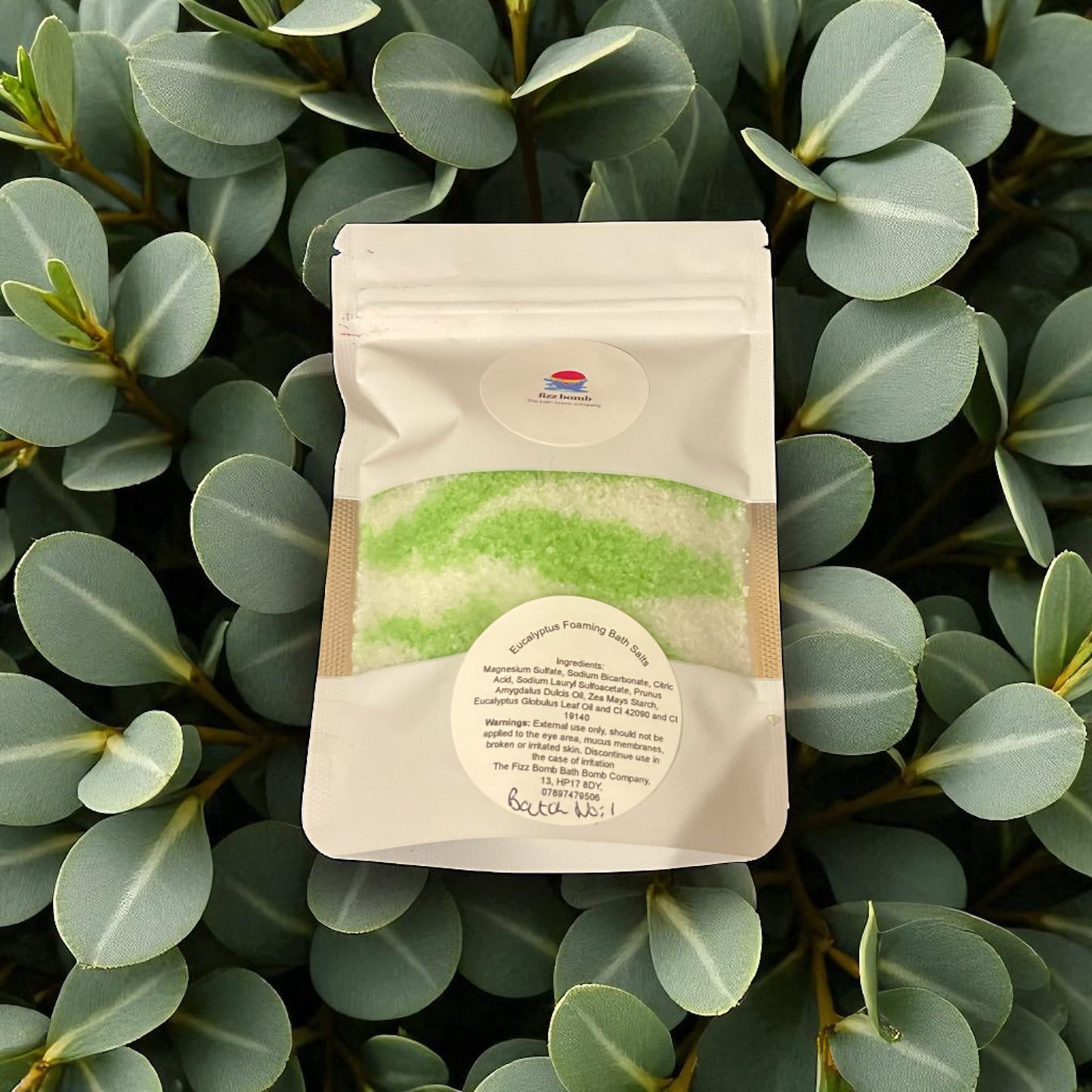 A bag of green and white coloured foaming Bath salts with a eucalyptus leaves background