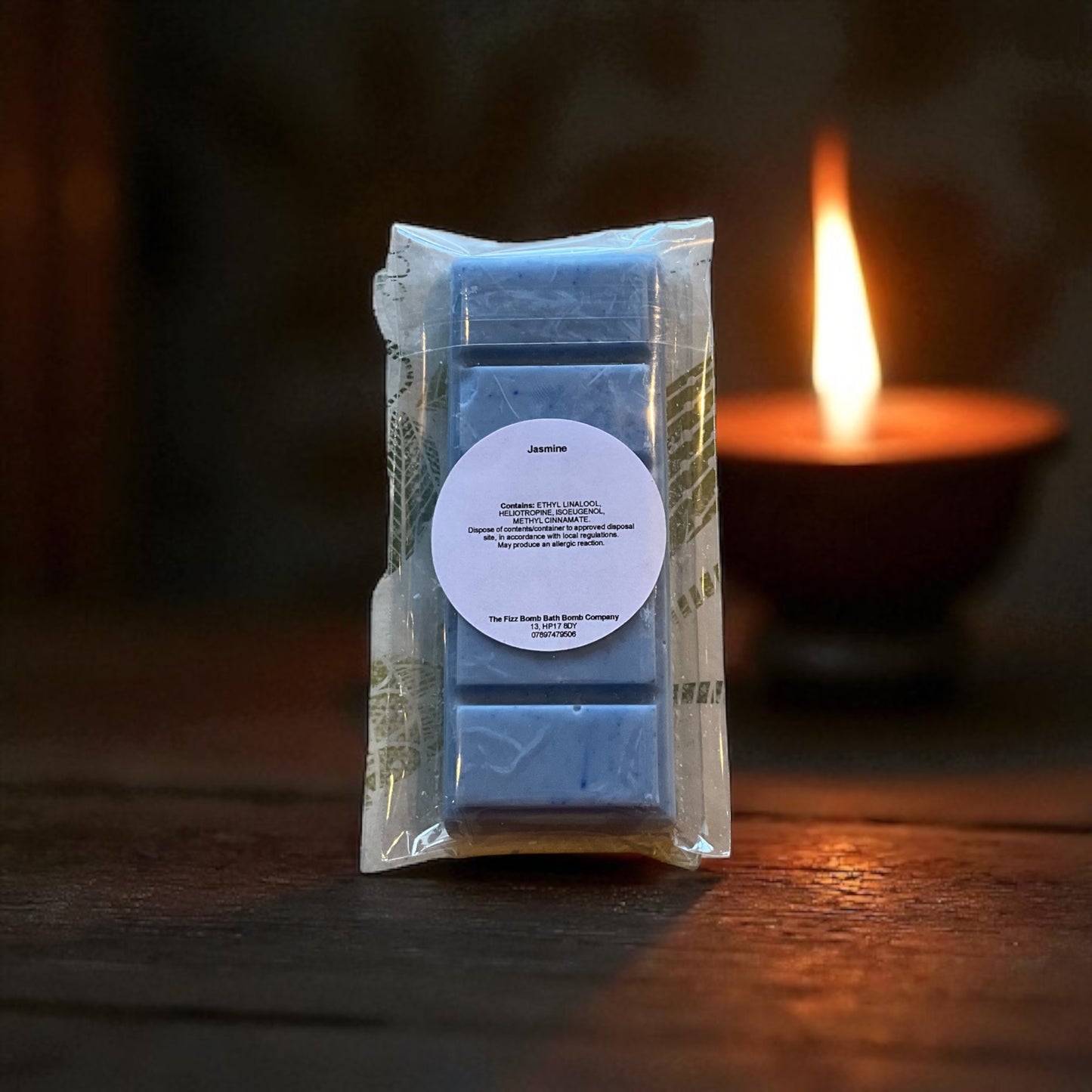 Packaged blue wax melts with a candle in the background