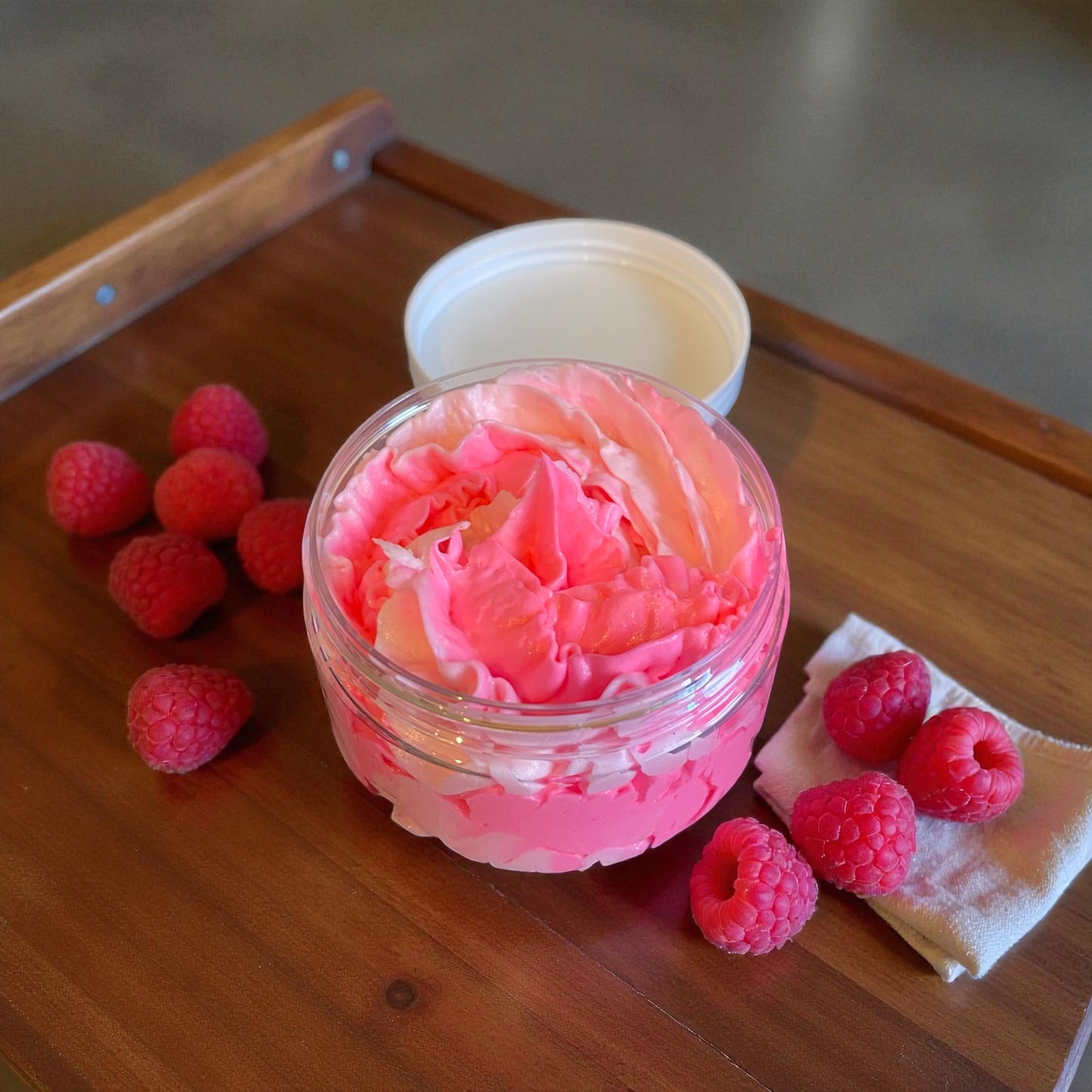 A pink hand piped whipped soap in a plastic jar.