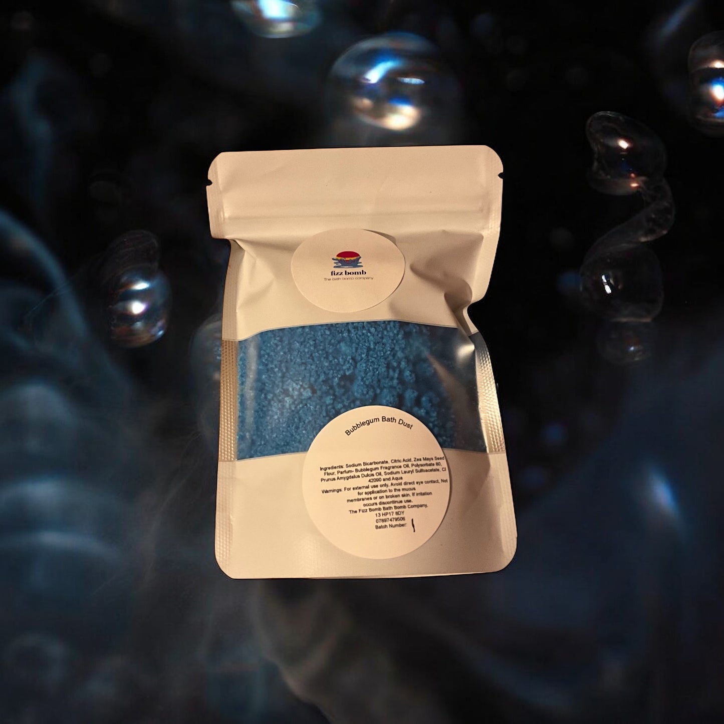 Beige packaging of blue bath dust with a label on a dark background