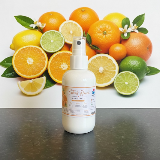A white spray bottle labeled Citrus Haven Body Spray stands on a dark tabletop in front of a large citrus fruit display featuring oranges, lemons, limes, and small white flowers.