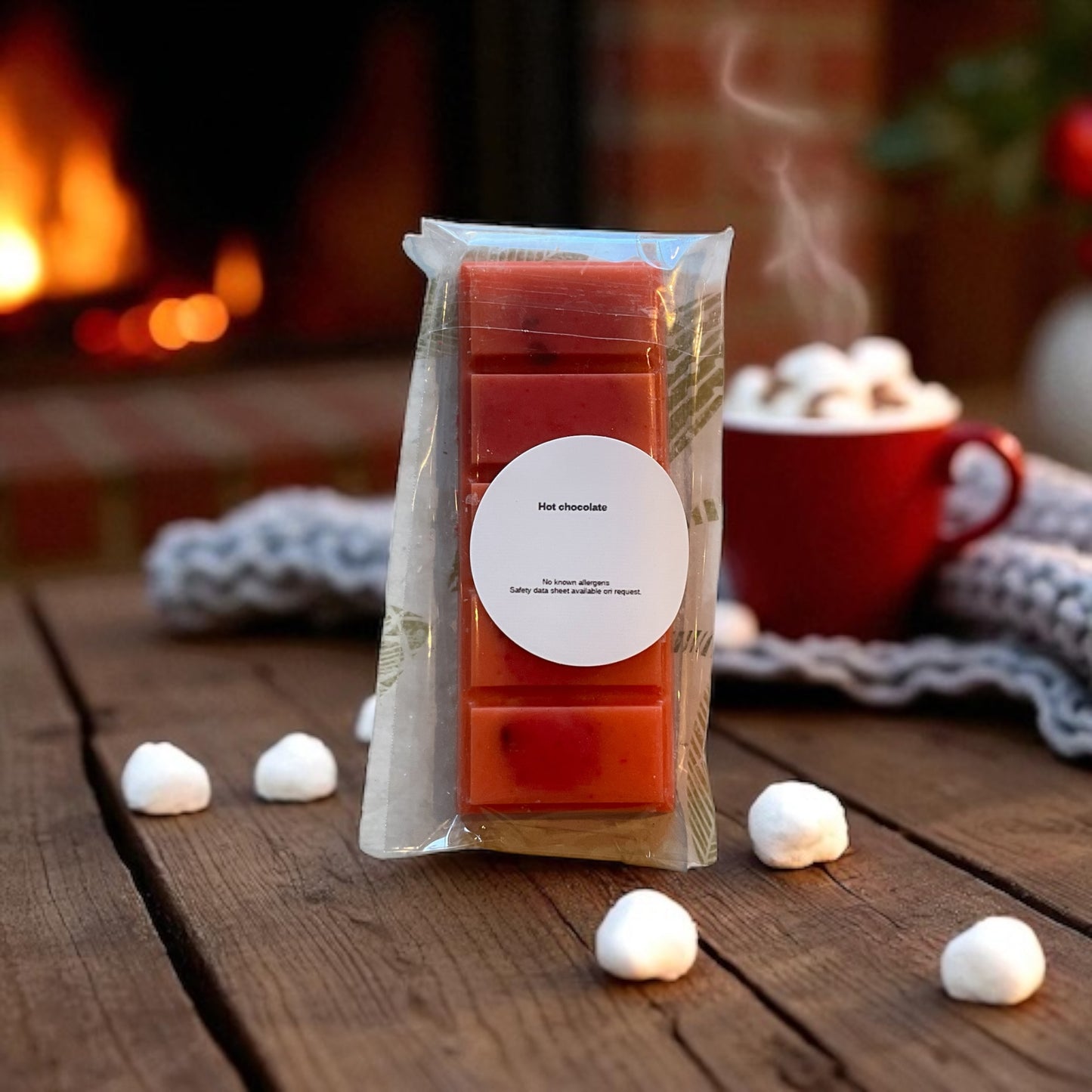 Pack of wax melts with a hot chocolate scent on a wooden surface in front of a fireplace.