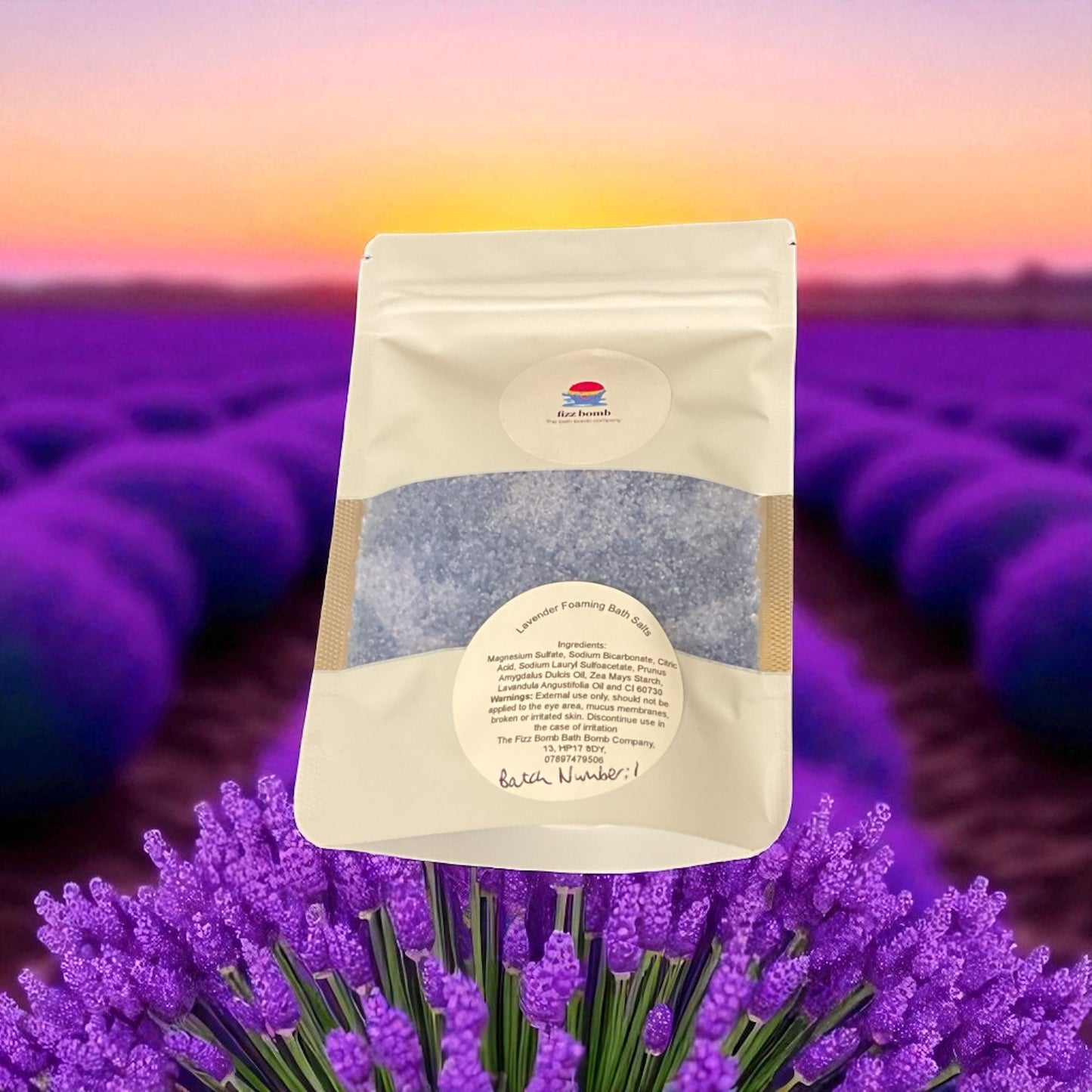 A bag of violet coloured bath salts with a lavender background.