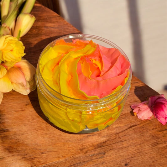 A hand piped pink and yellow whipped soap in a plastic jar