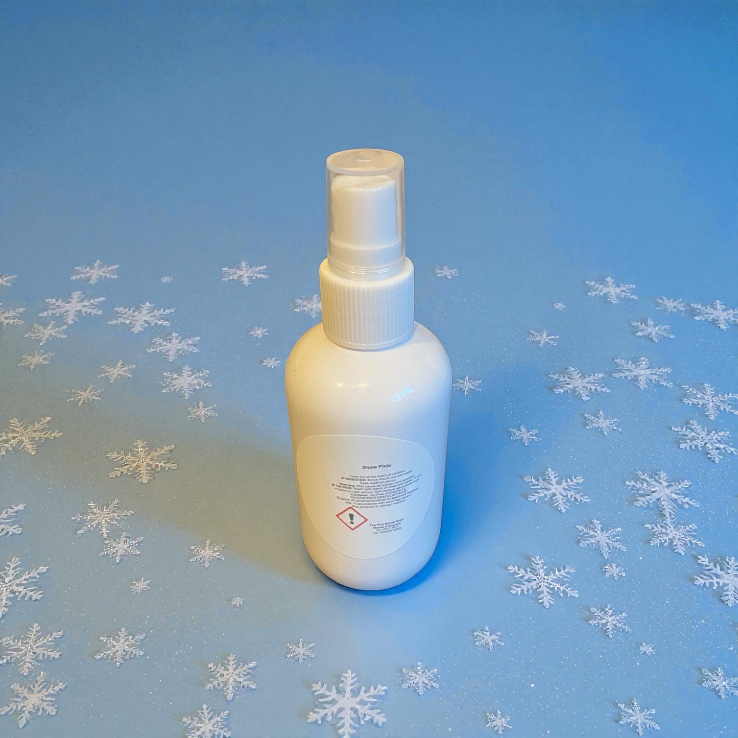White spray bottle on a blue background with snowflake patterns