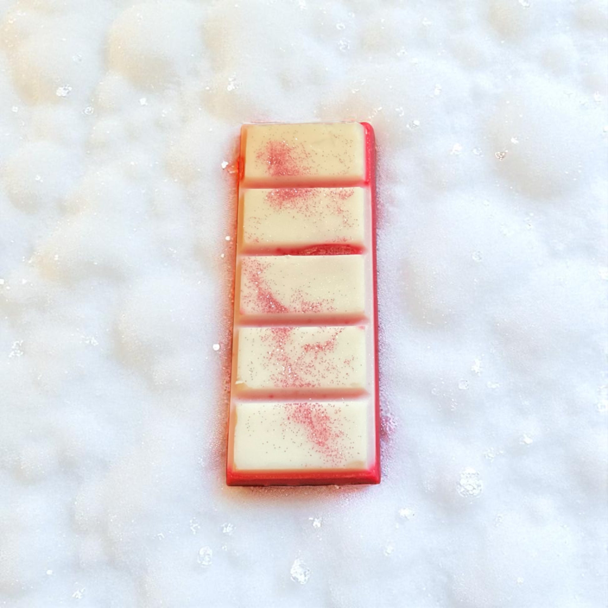 A pink and white glittery wax melt with a snowy themed background
