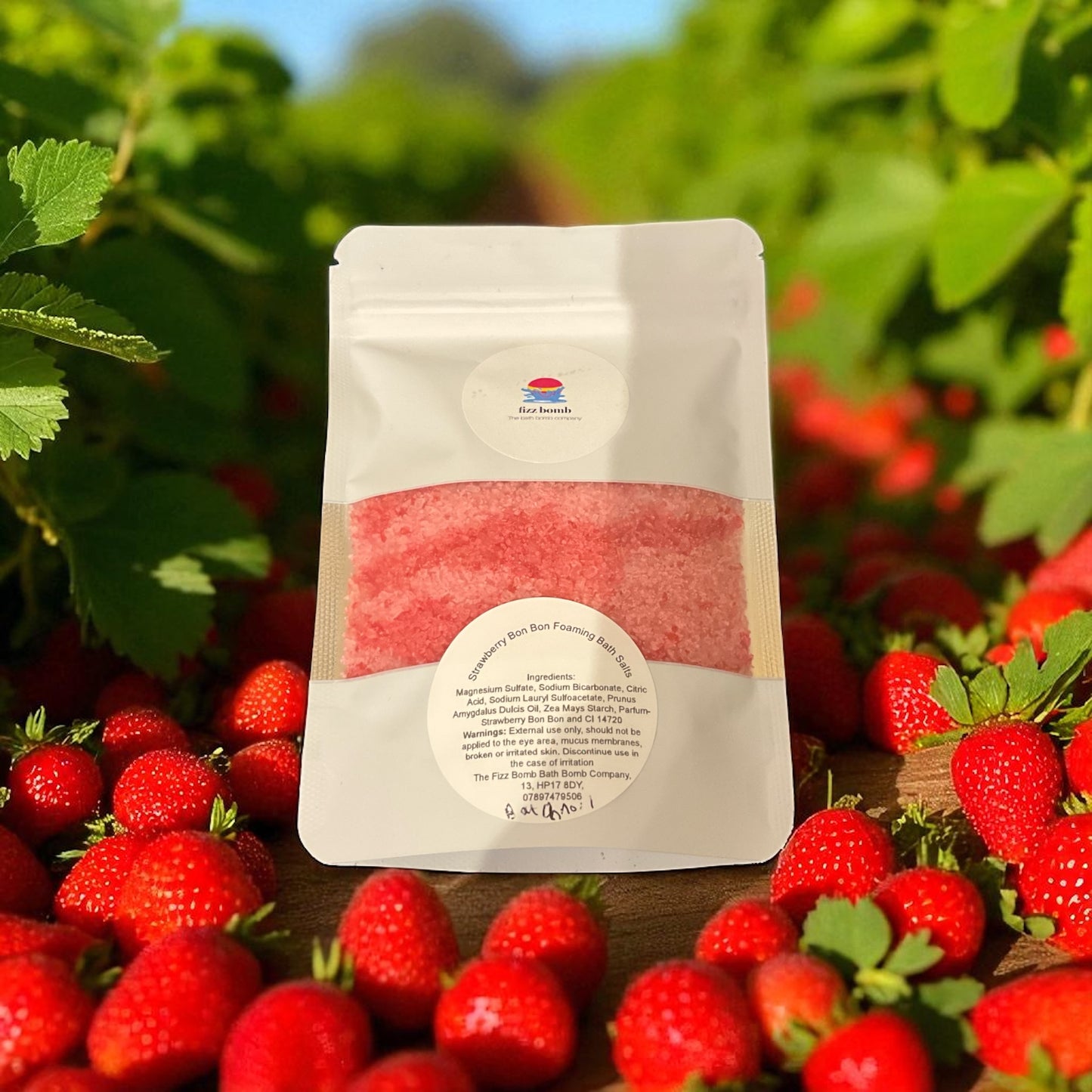A bag of red coloured bath salts with a strawberries background